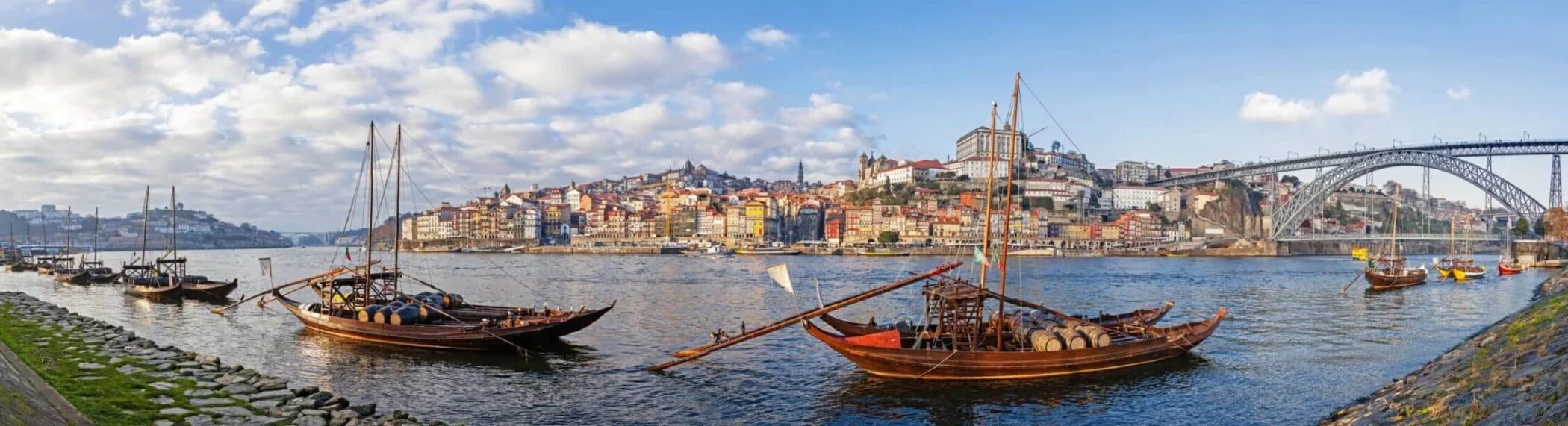 Portvine, der fuldender ethvert måltid og stjernestund 1 The iconic Rabelo Boats, the traditional Port Wine transports, with the Ribeira District and the Dom Luis I Bridge over the Douro River. Porto, Portugal. Unesco World Heritage.