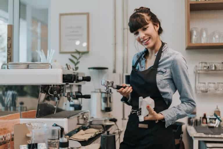 Specialkaffe. Glad kvinde kaffeejer stående bag disken på en kaffebar.