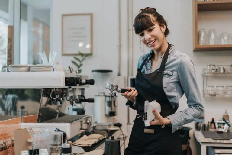 Winetalk er til alle, der elsker god vin og mad 16 Specialkaffe. Glad kvinde kaffeejer stående bag disken på en kaffebar.