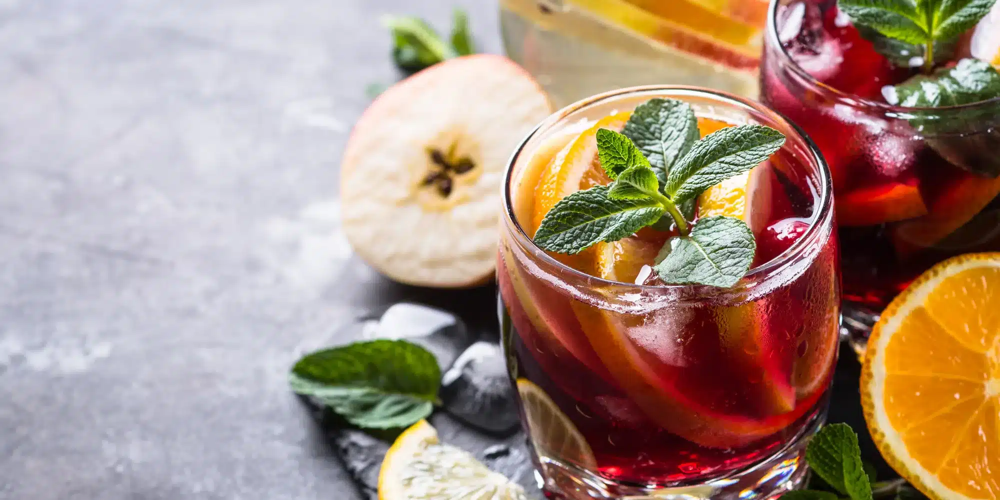 Sangria with fruit, ice and mint in glass.