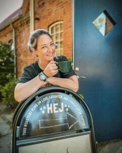 Ubuntu-coffee-Caryn-in-front-of-roastery-with-cup-of-coffee